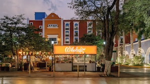 A restaurant named "La Arboleda Bistro & Grill" with outdoor seating and a view of a red building with white trim and multiple windows.