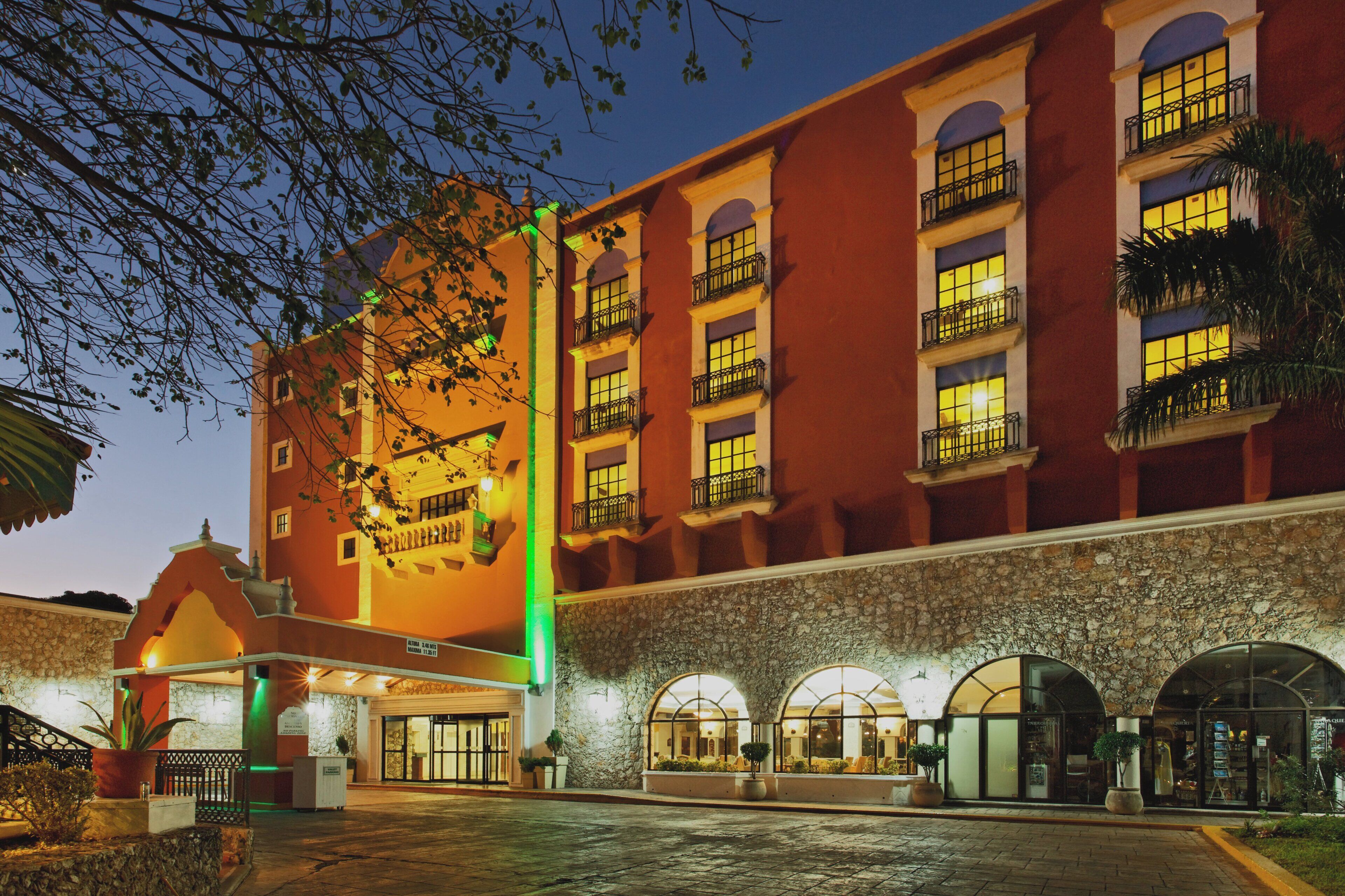 A hotel with a red facade, multiple balconies, and a stone facade entrance.