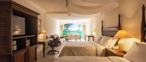 A hotel room with two beds, a desk, a chair, a television, and a view of a garden through a window.