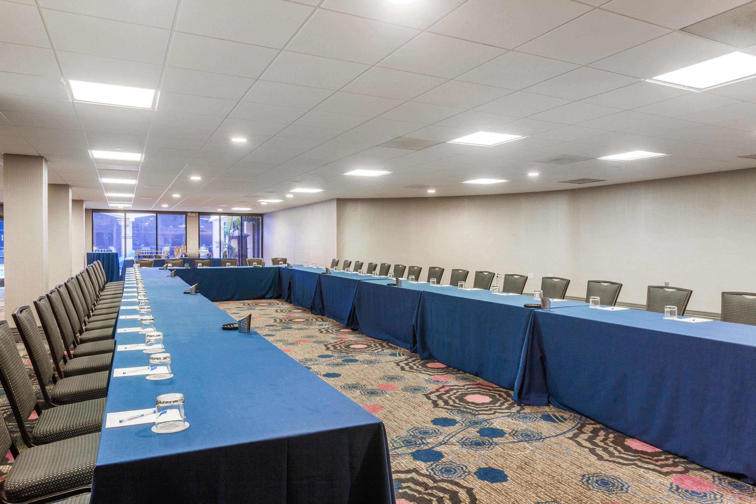A conference room with a long table, chairs, and a carpeted floor.