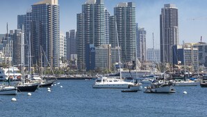 Una marina con diverse imbarcazioni ormeggiate e alti edifici sullo sfondo.