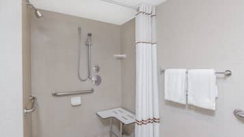Un baño moderno con ducha, barras de apoyo, un asiento y un perchero para toallas.