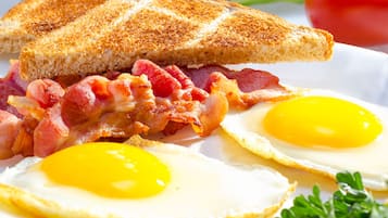 A plate with a grilled sandwich, bacon, and two fried eggs.