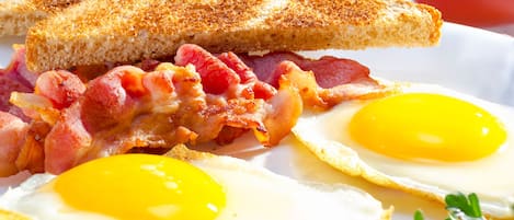 A plate with a grilled sandwich, bacon, and two fried eggs.