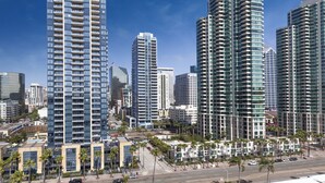 Zona urbana con edifici moderni, palme e cielo sereno.