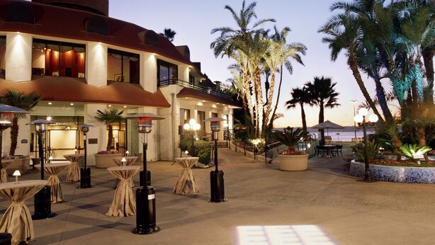 Cortile di un hotel con posti a sedere all'aperto, palme e vista sull'oceano al crepuscolo.
