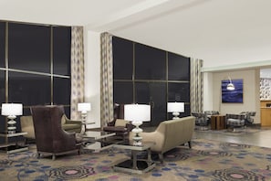 Een ruime lobby met een groot raam, een bank, fauteuils en een salontafel.