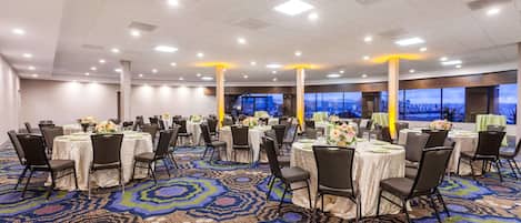 A large conference room with round tables, chairs, and a patterned carpet.