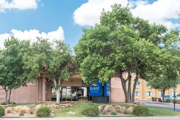 A hotel with a prominent "Baymont" sign, surrounded by mature trees and landscaped gardens.