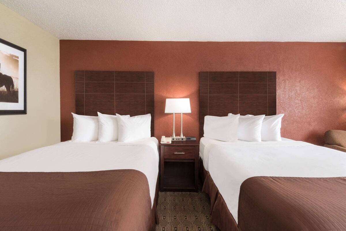 Une chambre d’hôtel avec deux lits, une table de chevet avec une lampe et un tableau encadré au mur.