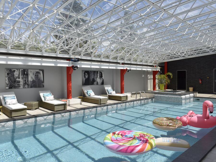 Een binnenzwembad, ligstoelen bij het zwembad