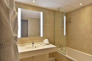 A modern bathroom with a glass-enclosed shower, a white sink with toiletries, and a large mirror. - Hôtel Arles Plaza (Arles)
