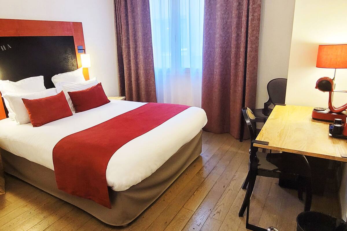 A hotel room with a large bed, a desk, and a chair.