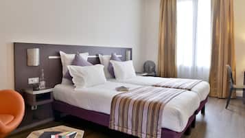 Una habitación de hotel con una cama grande, una mesita de noche, una silla y una mesita auxiliar.