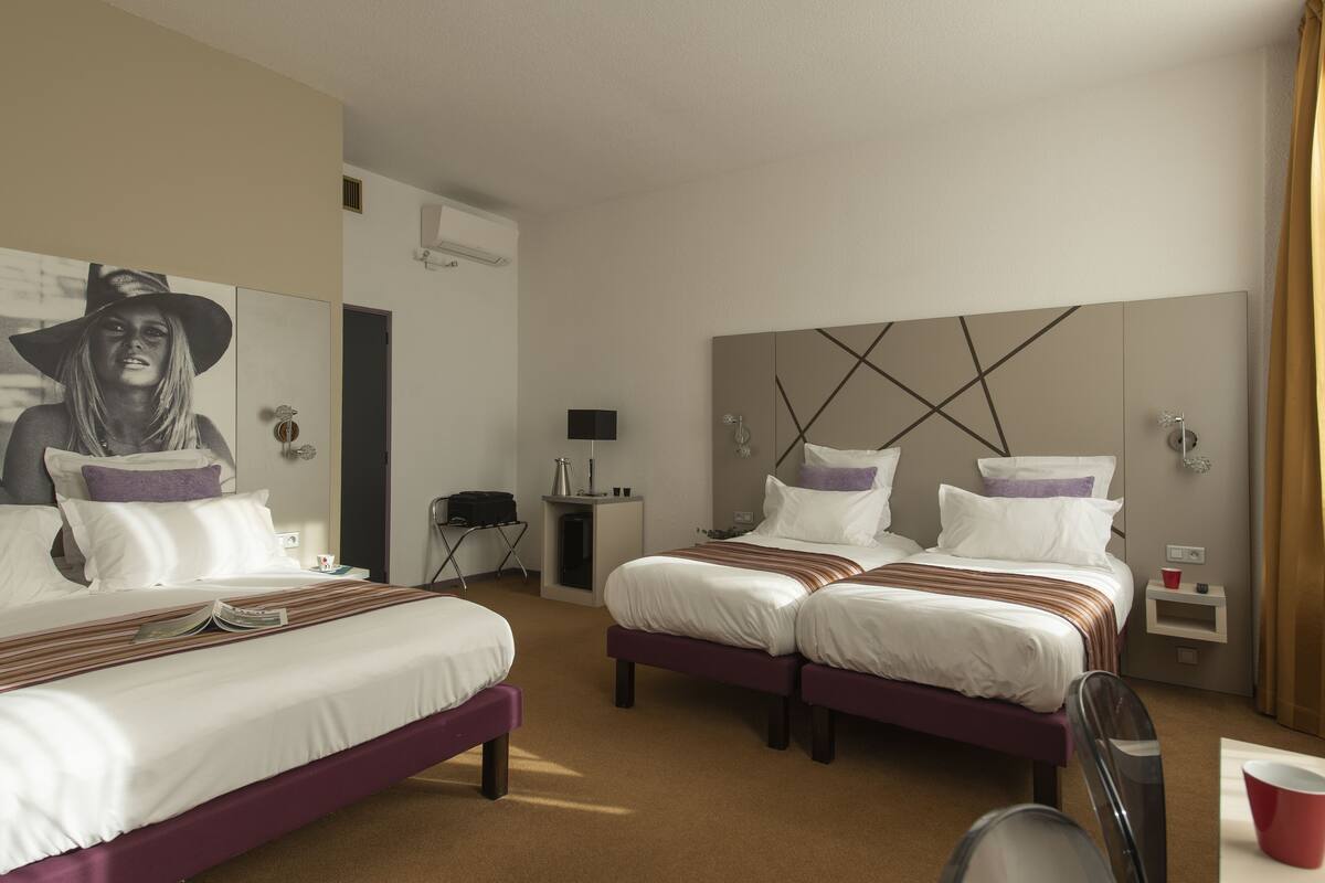 A hotel room with two beds, a small desk, a chair, and a mirror.