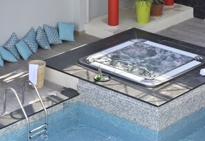 A hot tub with a tiled edge, a metal ladder, and a glass panel. - Hôtel Arles Plaza (Arles)