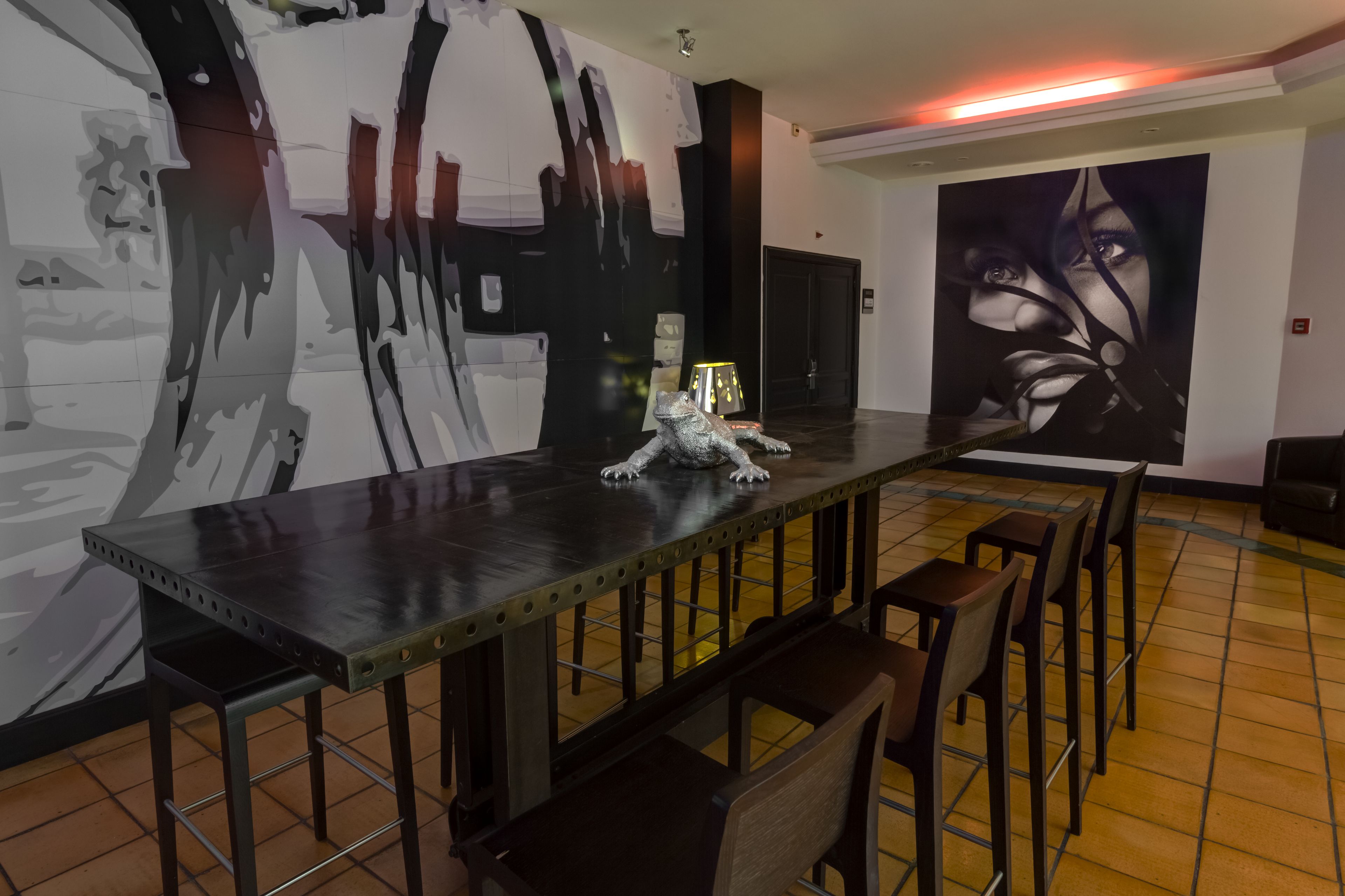 A bar area with a long counter, stools, and a large abstract mural on the wall.