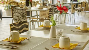 A dining area with tables set for service, chairs, and a large window providing natural light. - Hôtel Arles Plaza (Arles)