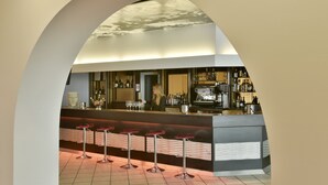 A bar area with a modern design, featuring a counter, bar stools, and a variety of bottles and glasses. - Hôtel Arles Plaza (Arles)
