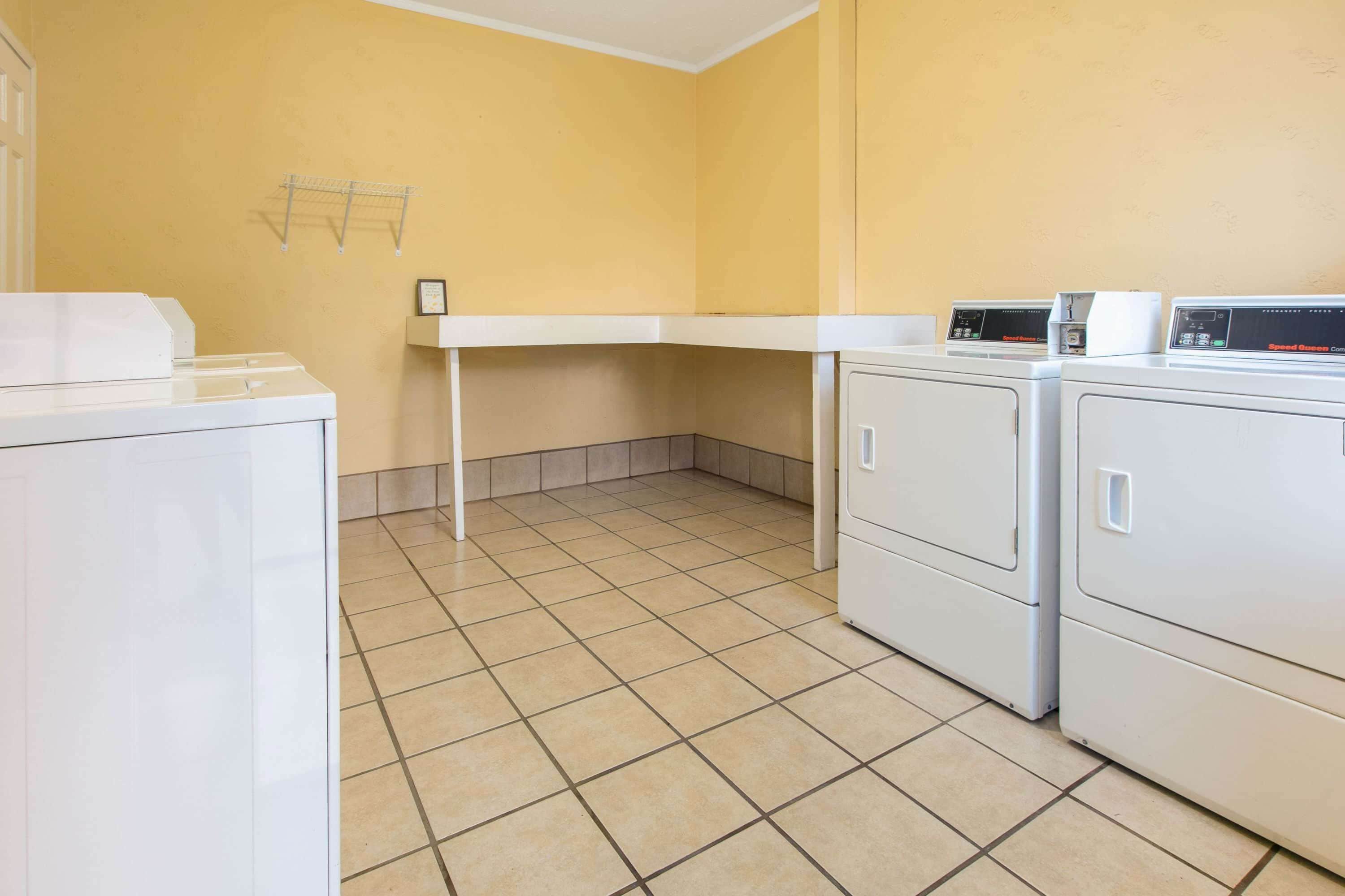 A laundry room with a washing machine, dryer, and a shelf with a towel rack.