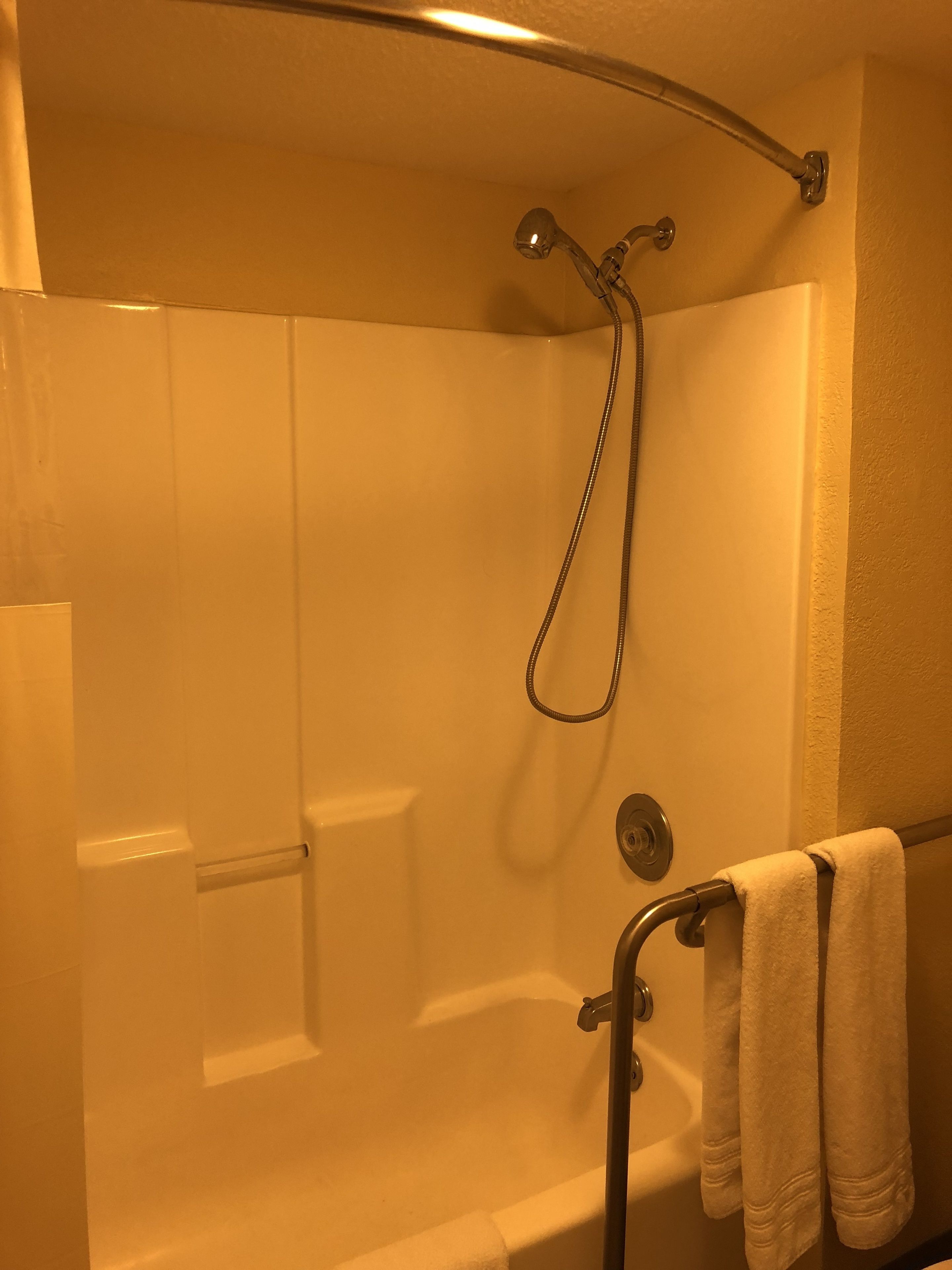 Un baño moderno con ducha de vidrio, bañera y un perchero con toallas.