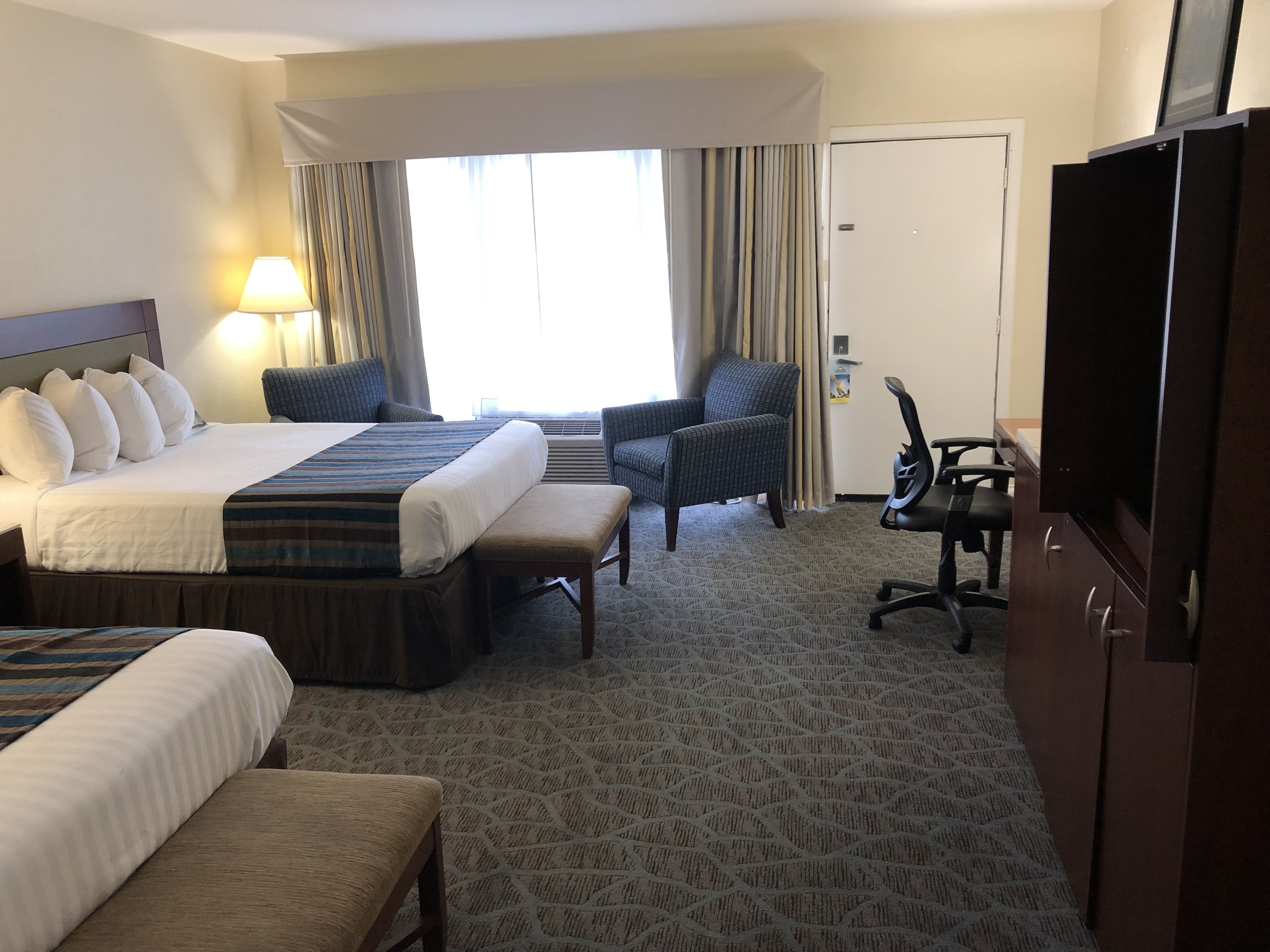 Habitación de hotel con una cama grande, un escritorio, una silla y un televisor.