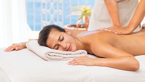 A massage therapy session in a room with a balcony overlooking the sea.