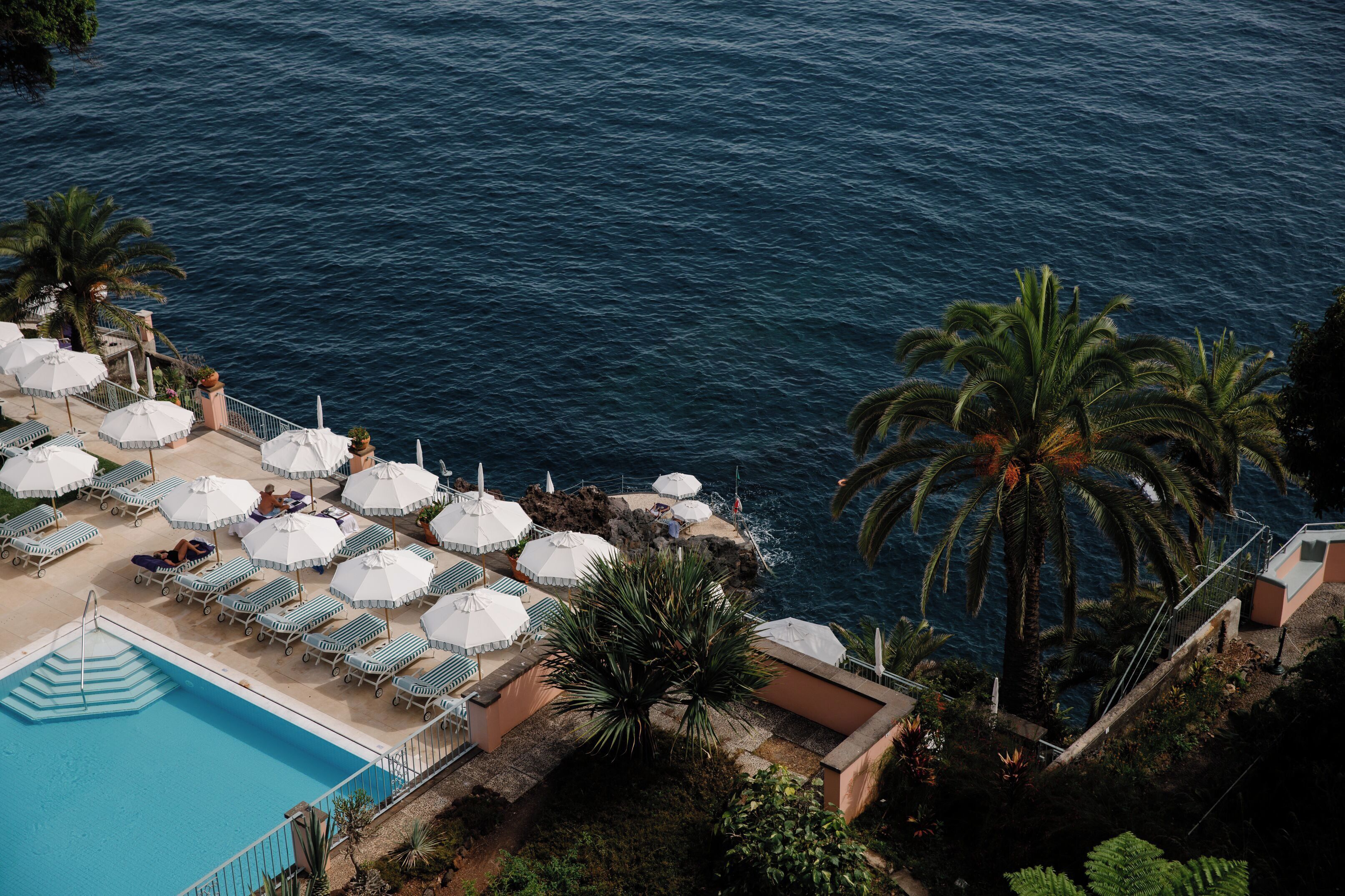 A poolside area with lounge chairs and umbrellas, overlooking a body of water.