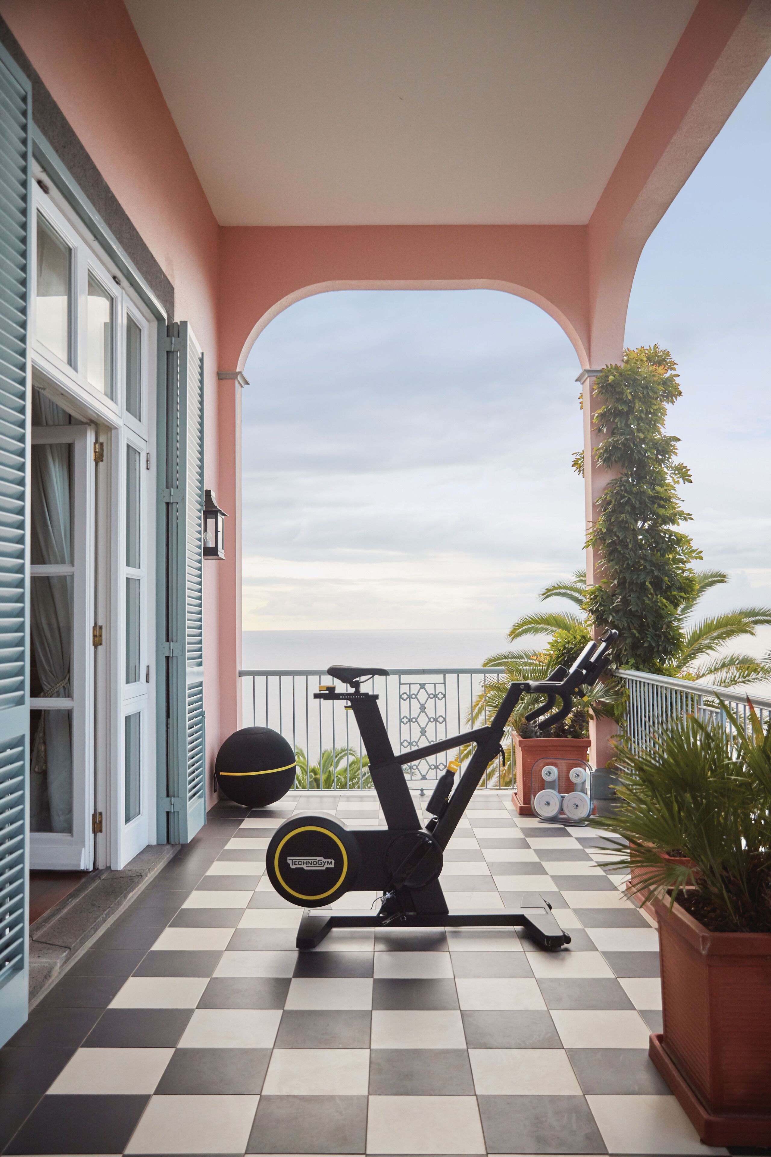 Un balcon doté d’un sol à carreaux, d’un vélo d’appartement et offrant une vue sur la mer.