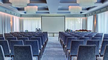 A conference room with rows of chairs, a projector screen, and a large screen.