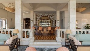 A bar area with a patterned floor, bar stools, and a bar counter with bottles.