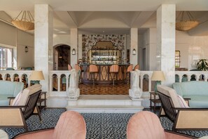 A bar area with a patterned floor, bar stools, and a bar counter with bottles.