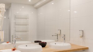 A modern bathroom with two sinks, a large mirror, and a towel rack.