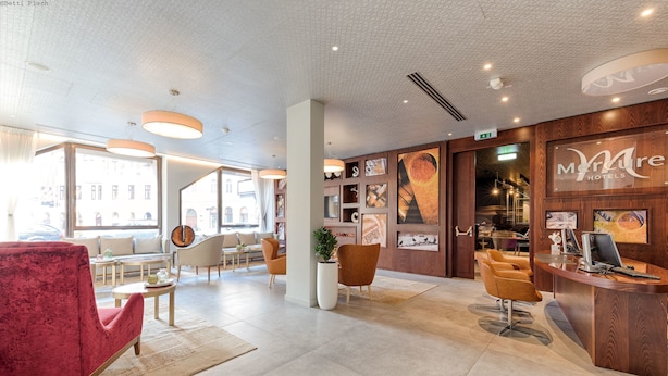 A hotel lobby with a reception desk, seating area, and large windows. - The Raphael Vienna Hotel, a member of Radisson Individuals Boutique (Vienna)