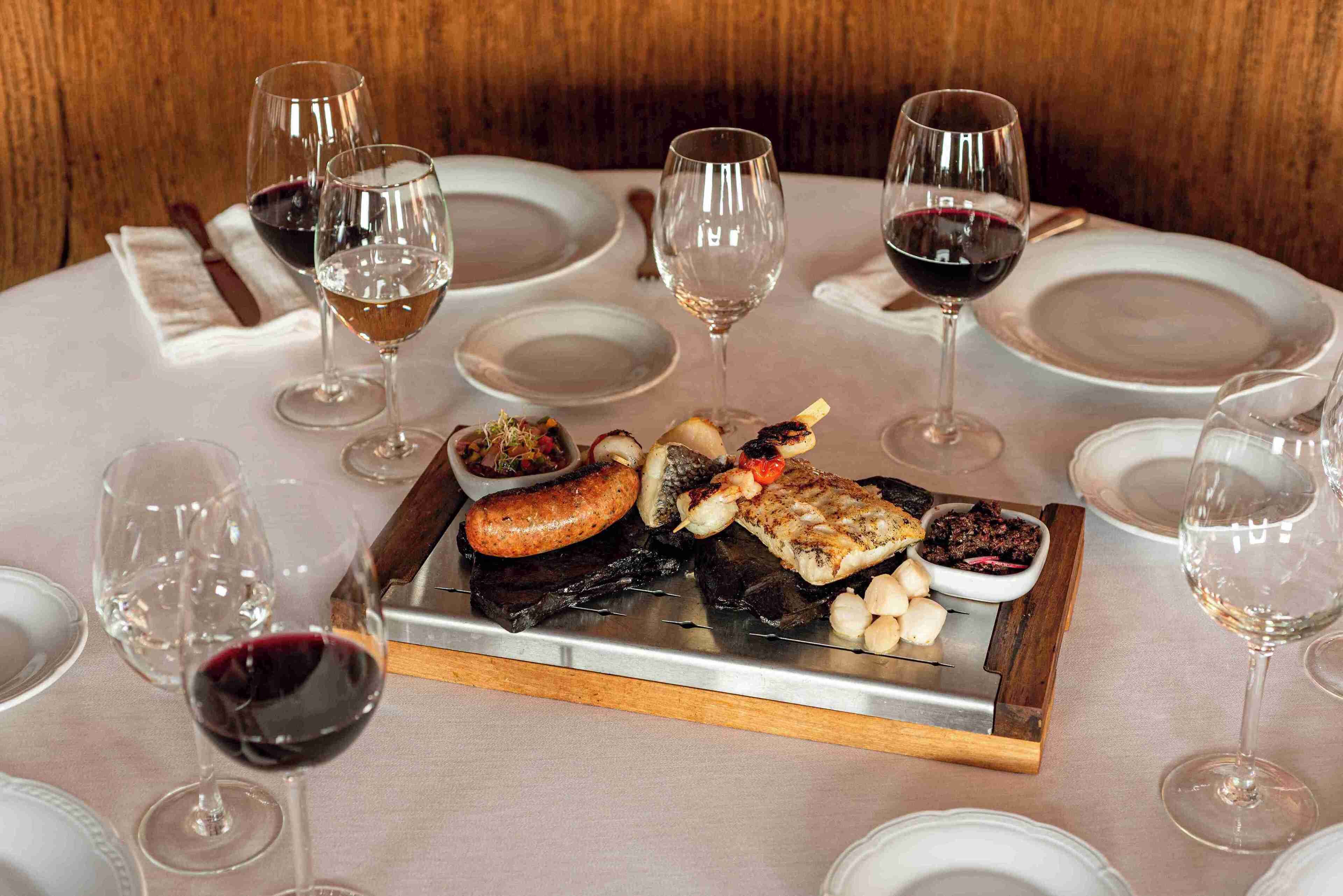 A dining table with a variety of food items and wine glasses.