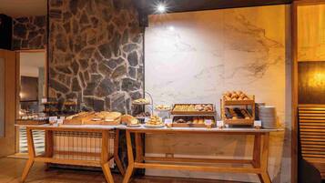 Un buffet de petit-déjeuner proposant une variété de viennoiseries et de pains, le tout dans un cadre constitué de murs en pierre et en marbre.