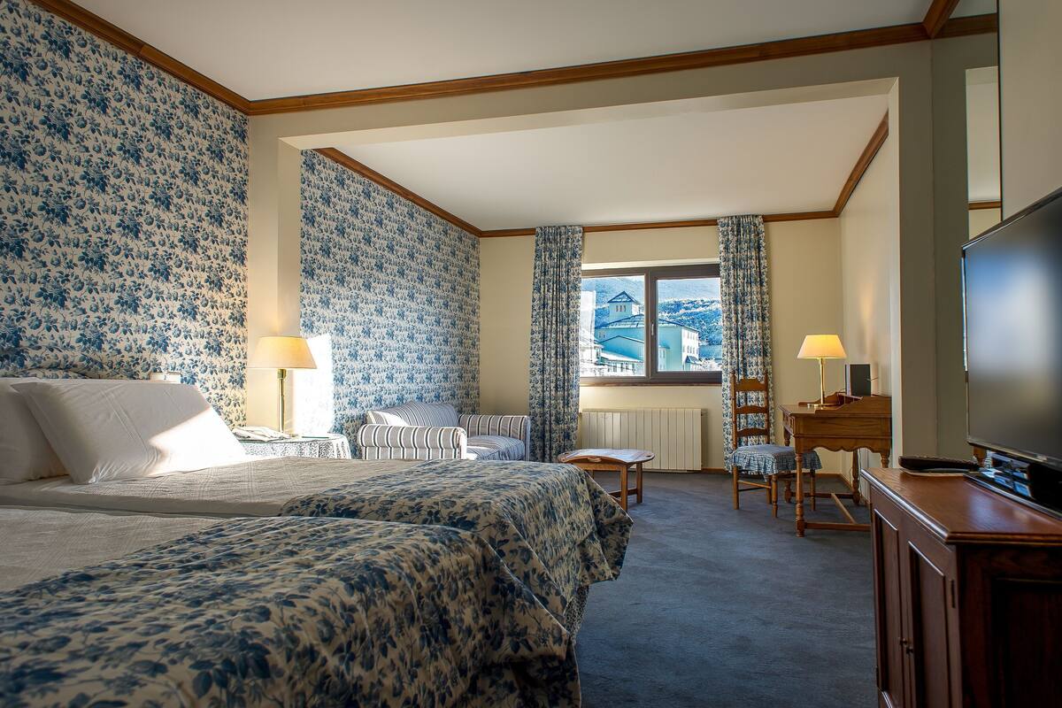 Une chambre d’hôtel avec deux lits, une télévision, un bureau et une vue sur la montagne.