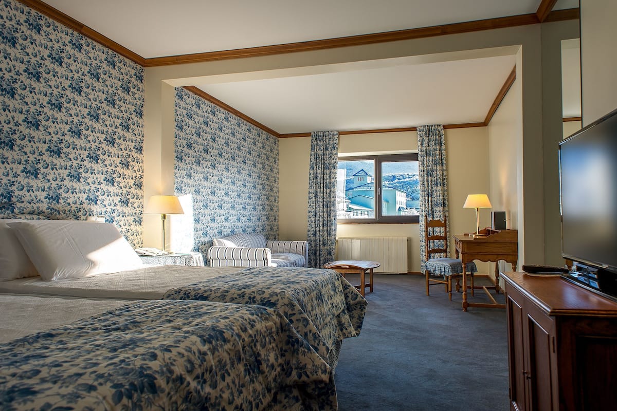 Une chambre d’hôtel avec deux lits, une télévision, un bureau et une vue sur la montagne.