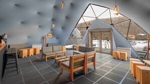 Een gezellig interieur met een geometrisch plafond, houten meubels en uitzicht op het omliggende landschap.