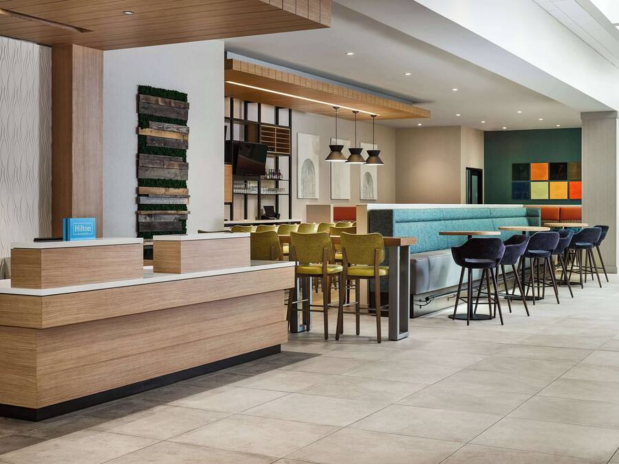 Un hall d’hôtel moderne comprenant un comptoir d’accueil, un espace salon et des panneaux muraux décoratifs.