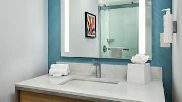 A modern bathroom with a large mirror, two sinks, and a shower.