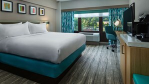 A hotel room with a large bed, a desk with a computer, a TV, and a view of the outdoors. - Hilton Garden Inn Tewksbury Andover (Tewksbury)