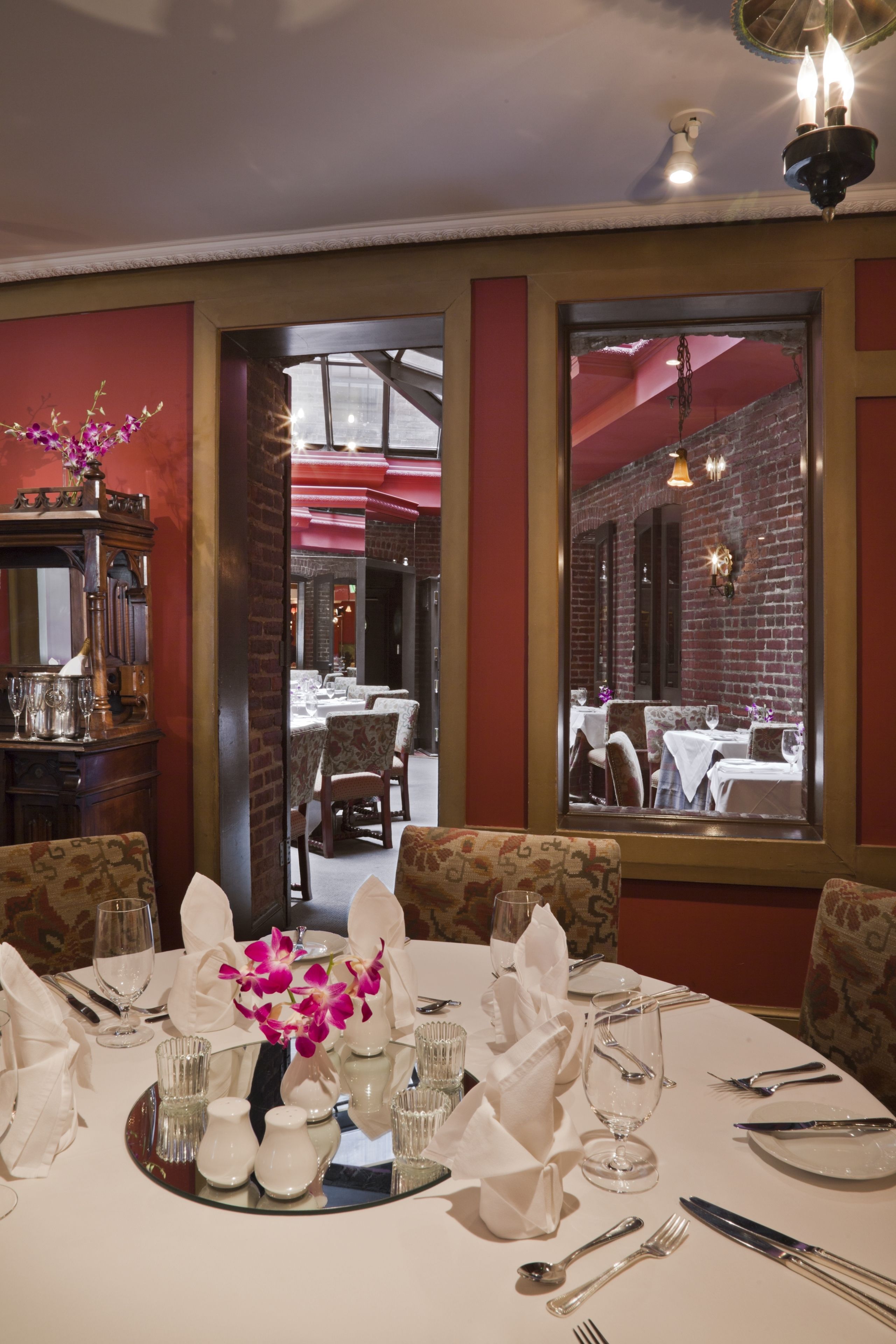 A dining area with a table set for four, including a vase of flowers, glasses, and cutlery.