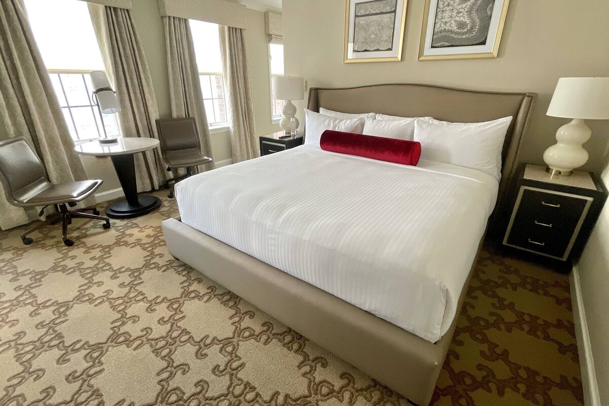 A hotel room with a large bed, a desk, a chair, and two bedside tables.