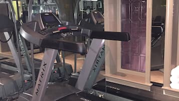 A treadmill with a control panel and a mirrored wall.