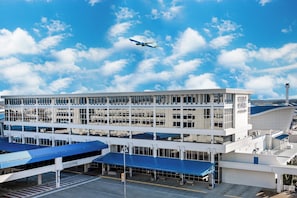 A modern airport terminal with a clear sky and an airplane in flight. - Four Points by Sheraton Huntsville Airport (Huntsville)