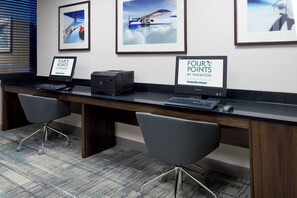 A reception desk with a computer, printer, and two chairs. - Four Points by Sheraton Huntsville Airport (Huntsville)