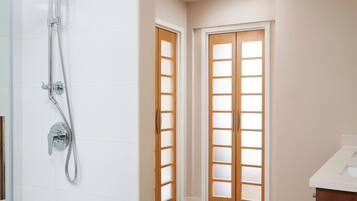 Un baño moderno con ducha, bañera y puerta de madera con paneles de vidrio esmerilado.