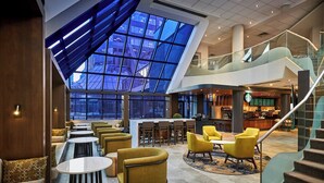 A spacious lobby with a high ceiling, a central staircase, and a Starbucks coffee shop. - Delta Hotels by Marriott Toronto Mississauga (Mississauga)