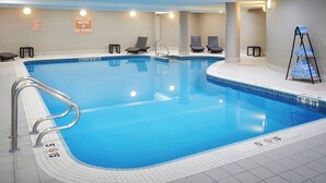 A large indoor swimming pool with a shallow water sign, lounge chairs, and a towel rack. - Delta Hotels by Marriott Toronto Mississauga (Mississauga)